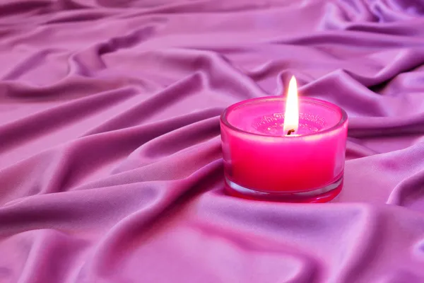 Romantic pink candle on a silk fabric — Stock Photo, Image