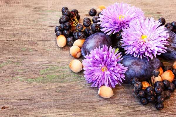 Autumn flowers, ash berries and nuts on a wooden background — Stock Photo, Image