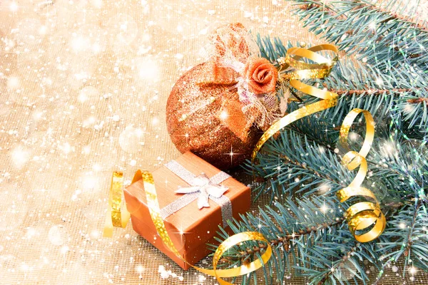 Beautiful golden ball, gift box and christmas tree branches — Stock Photo, Image