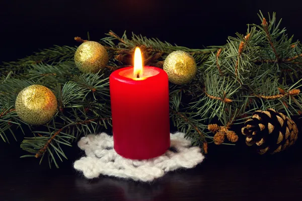 Красная свеча на трикотажной праздничной салфетке и рождественских украшениях — стоковое фото