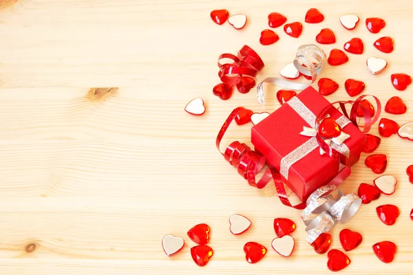Caja de regalo roja, cintas, corazones de San Valentín sobre un fondo de madera — Foto de Stock