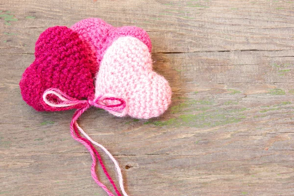 Knitted toys in the shape of hearts on an old wooden background — Stock Photo, Image