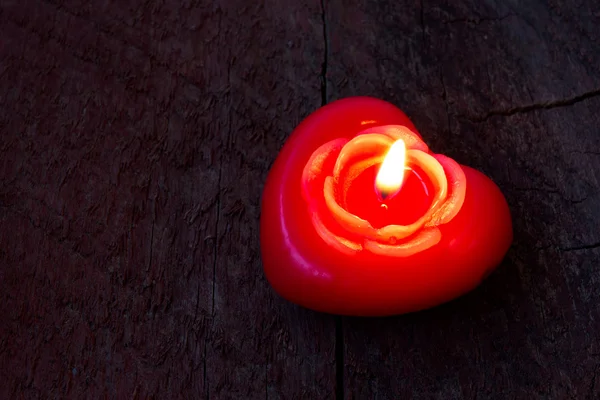 Red candle in the shape of heart on an old scratched wooden background — Stock Photo, Image