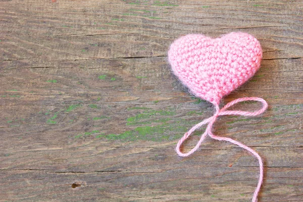 Pink knitted toy in the shape of heart on an old wooden background — Stock Photo, Image