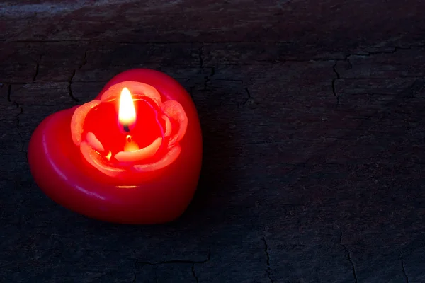 Red candle in the shape of heart on an scratched old wooden background — Stock Photo, Image