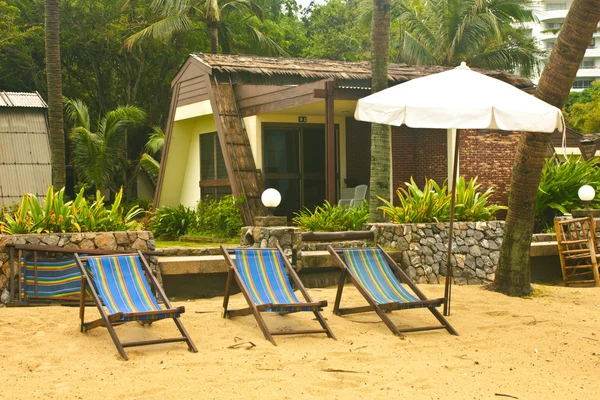Drei Liegestühle und Sonnenschirm am Strand — Stockfoto