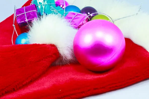 Mooie kerstmuts, giften en kerstballen op witte achterzijde — Stockfoto