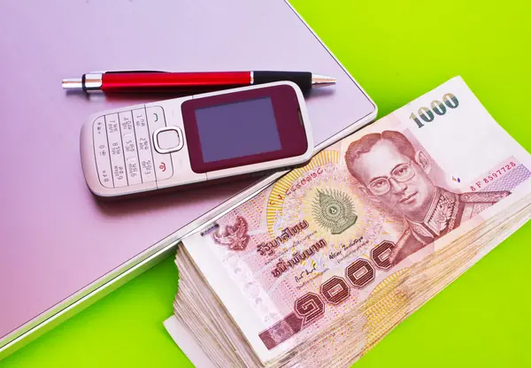 Cierre de billetes de 1000 baht y teléfono móvil en libreta — Foto de Stock