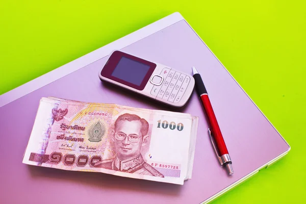 Nahaufnahme von 1000-Baht-Banknoten und Mobiltelefonen im Notizbuch — Stockfoto