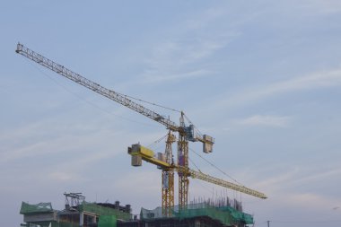 İnşaat vinçleri ve bitmemiş ev manzarası gösterir