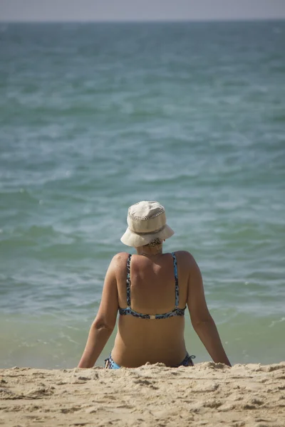 Wanita duduk di pantai dan menonton laut — Stok Foto