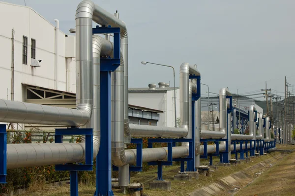 Zona industrial, dutos de aço e válvulas contra o céu azul — Fotografia de Stock