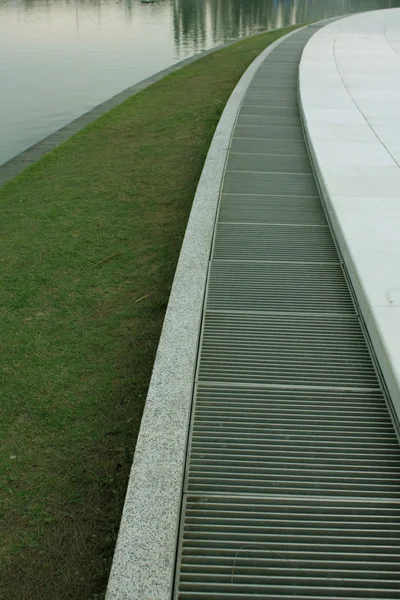 Água derretida flui para baixo através da tampa do bueiro — Fotografia de Stock