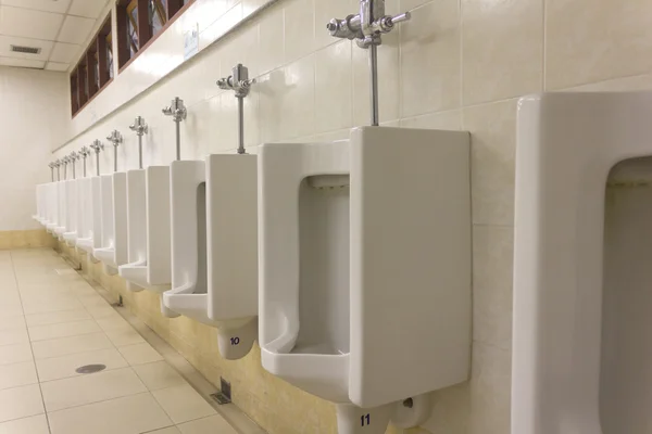 Uma fileira de urinóis na parede de azulejos em um banheiro público — Fotografia de Stock