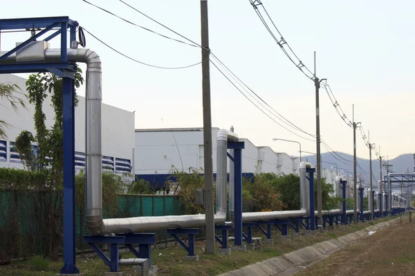 Zona industriale, tubazioni e valvole in acciaio contro il cielo blu — Foto Stock