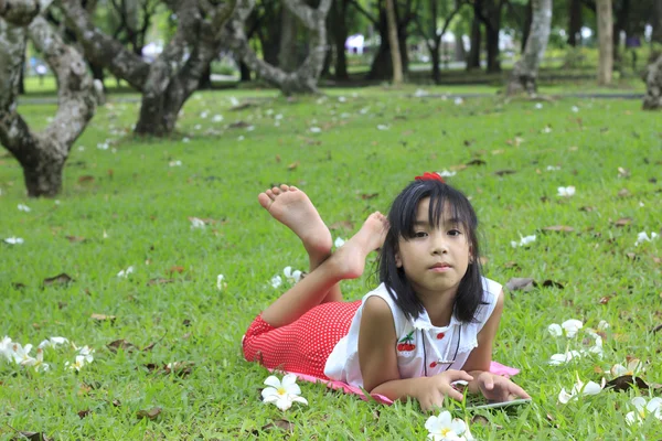 Giovane ragazza asiatica lettura qualcosa su tablet all'aperto — Foto Stock