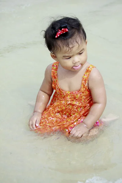 Asian baby first tasting the sea — Stock Photo, Image