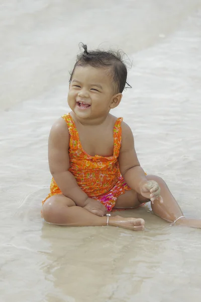 Asiatisches Baby lächelt auf Sand am Strand — Stockfoto