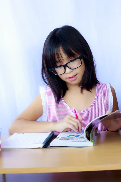 Porträt eines fröhlichen asiatischen jungen Mädchens, das seine Hausaufgaben macht — Stockfoto