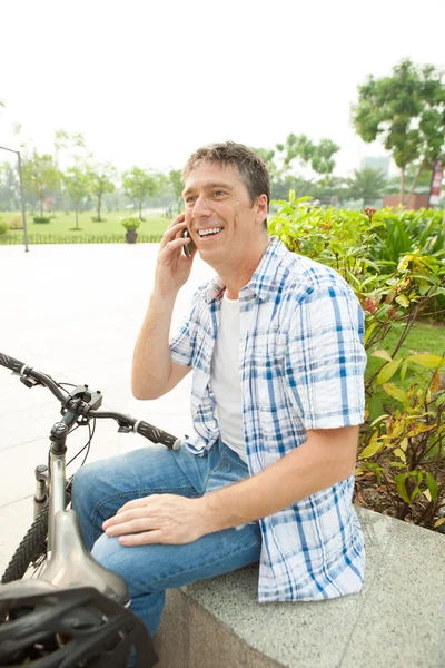 Onun bisiklet yakınındaki telefonla konuşan adam — Stok fotoğraf
