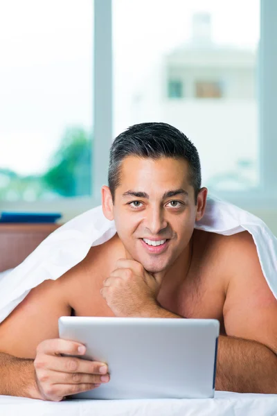 Hombre en la cama con touchpad —  Fotos de Stock