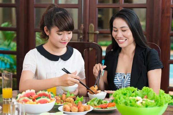 Mother and daughter dipping meat pieces — Stock Photo, Image