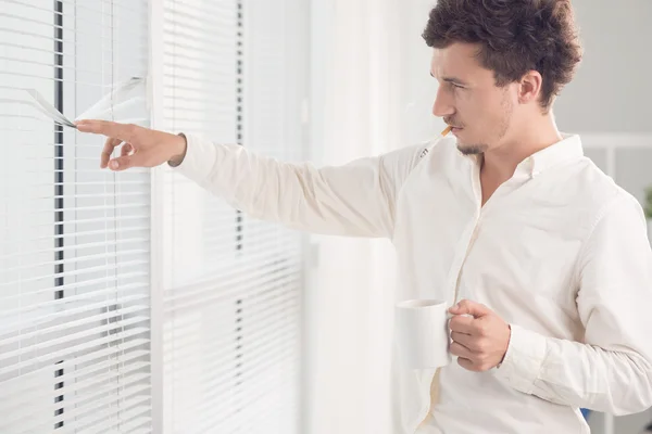 Man looking through blinds — Stock Photo, Image