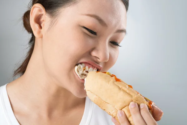 Asian woman biting a hot dog — Stock Photo, Image