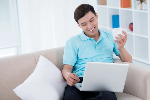 Mann trinkt Tee und benutzt Laptop — Stockfoto