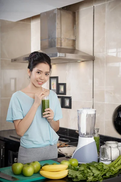 アジアの女性は台所でスムージーを飲む — ストック写真