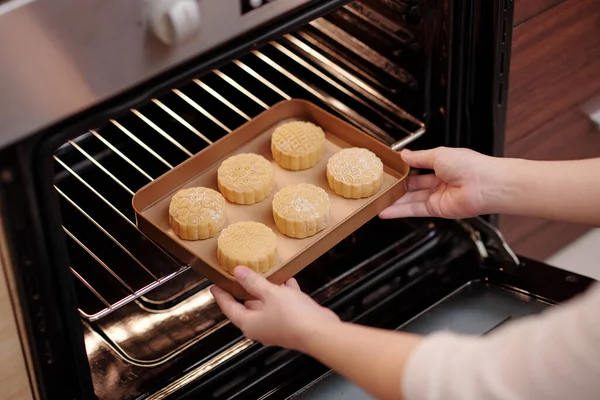 Mujer poniendo tartas de luna en el horno — Foto de Stock