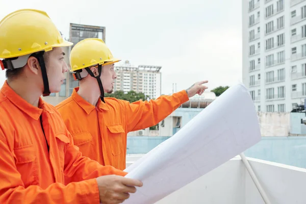 Trabajadores de la construcción señalando rascacielos —  Fotos de Stock