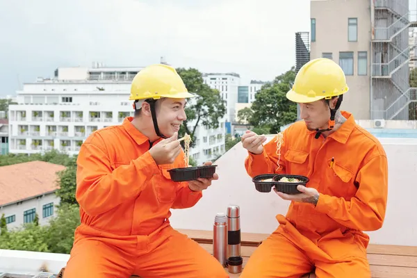 Budowniczowie jedzący lunch na dachu domu — Zdjęcie stockowe