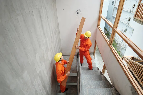 Trabalhadores transportando placa até escadas estreitas — Fotografia de Stock