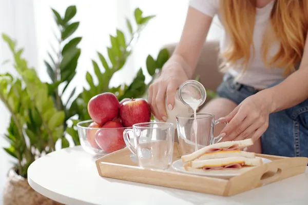 Vrouw gieten melk in bekers — Stockfoto