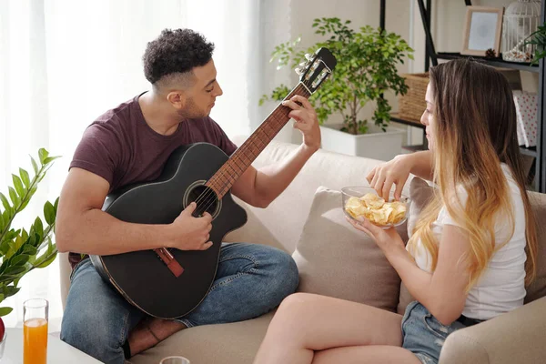 Vrouw op zoek naar vriendje spelen gitaar — Stockfoto
