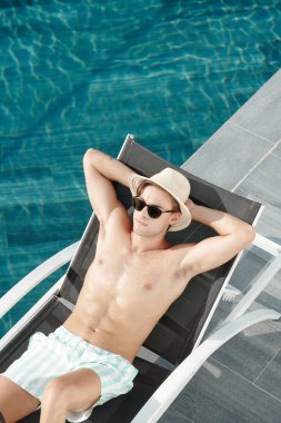 Şezlongda yatan kaslı adam.