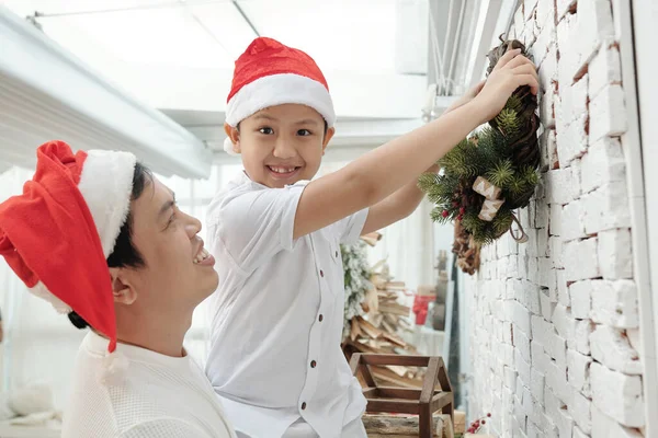 Padre e hijo colgando corona de Navidad —  Fotos de Stock