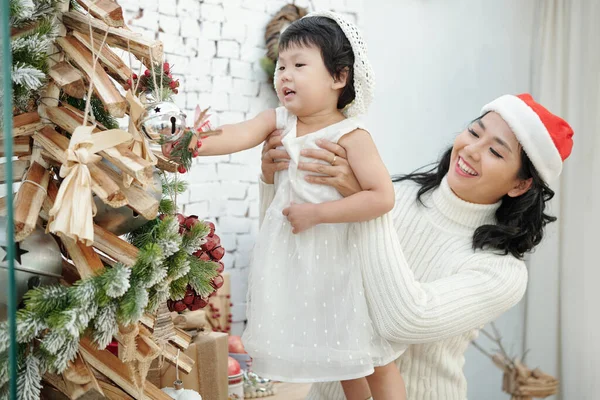 Mãe levantando filha árvore de decoração — Fotografia de Stock