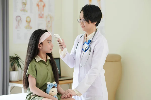 Lekarz sprawdzanie temperatury nastolatek dziewczyna — Zdjęcie stockowe