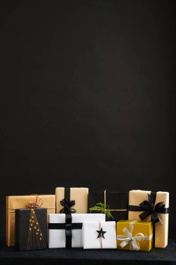 Siyah arkaplan ve Noel hediyeleri beyaz, siyah ve altın kağıda sarılı