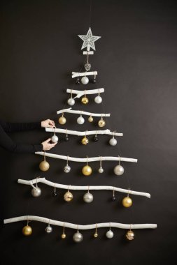 Ağaç dallarından Noel ağacı yapan kadınların elleri beyaza boyanmış ve mücevherlerle süslenmiş.