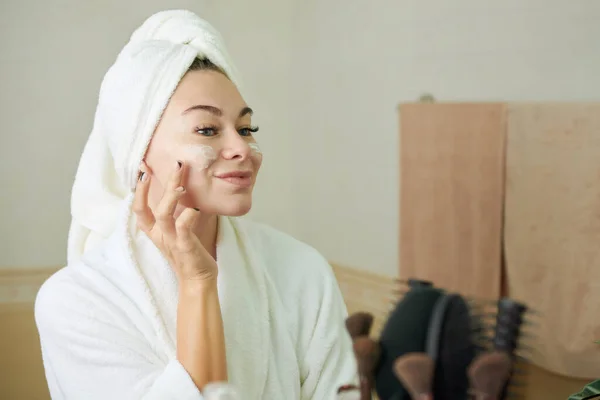 Mujer aplicando crema facial —  Fotos de Stock
