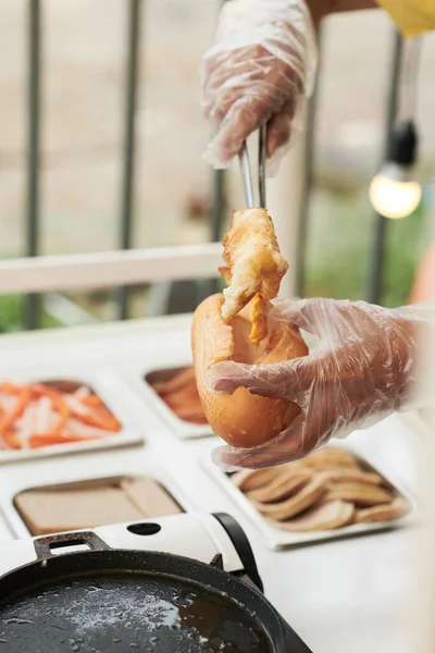 Verkäufer legt frittiertes Ei ins Brötchen — Stockfoto