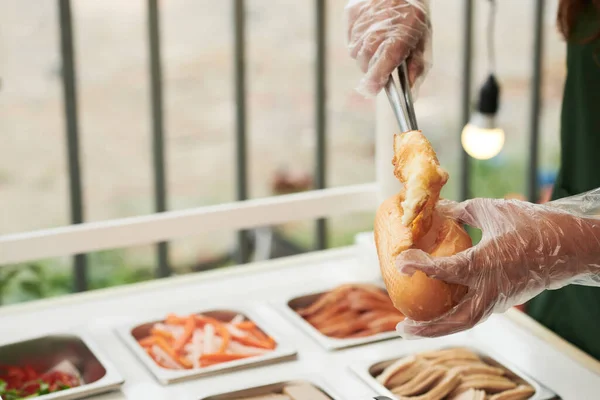 Fornitore che mette gli ingredienti nel panino — Foto Stock