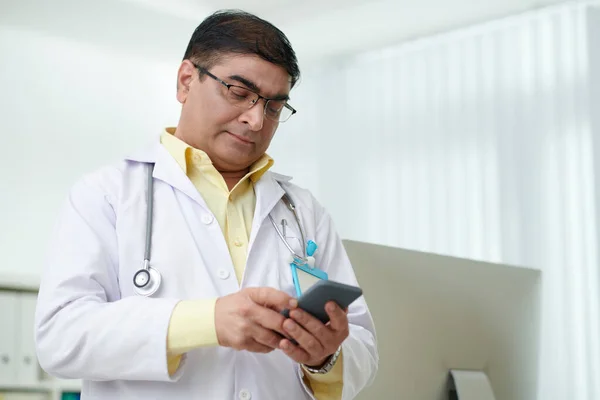 Arzt checkt Smartphone — Stockfoto