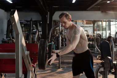 Halterin üzerine ağırlık plakası koyan adam