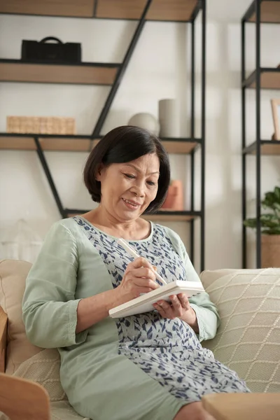 Seniorin schreibt Erinnerungen in Tagebuch — Stockfoto