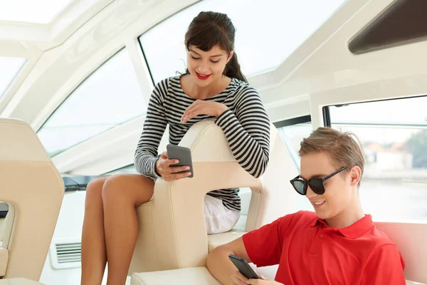 与智能手机在游艇上旅行的情侣 — 图库照片