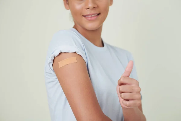 Menina mostrando polegar para cima após a vacinação — Fotografia de Stock